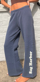 Person wearing blue sweatpants with 'Sag Harbor' text against a light brick wall.