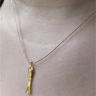 Gold fish pendant on silver chain necklace displayed on white mannequin neck