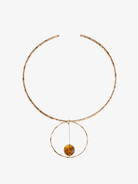 Hammered rose gold collar necklace with circular pendant holding amber bead on white background