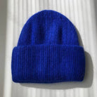 Bright royal blue ribbed knit beanie hat with folded cuff, soft fuzzy wool blend texture, laid flat on white surface.
