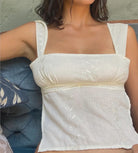 White lace top worn by a person with a neutral background
