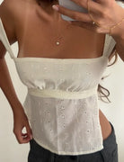 Woman wearing a white floral top with a plain background