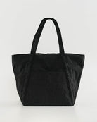 Black leather tote bag with twin handles and front slip pocket against light gray background