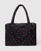 Black quilted tote bag with small red floral print pattern and padded handles