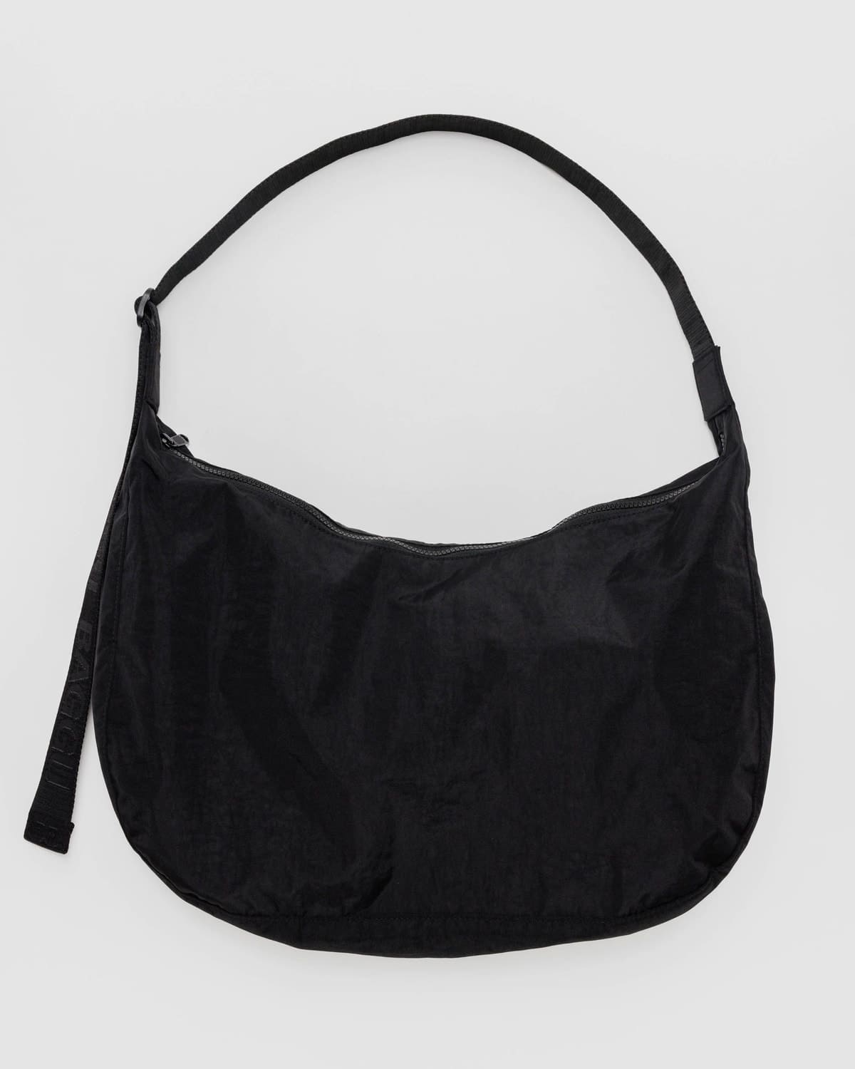 Black suede hobo shoulder bag with adjustable strap and curved crescent shape on white background