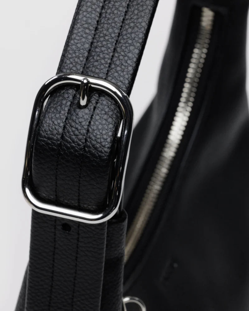 Black leather bag strap with silver rectangular buckle and textured grain finish, close-up detail shot