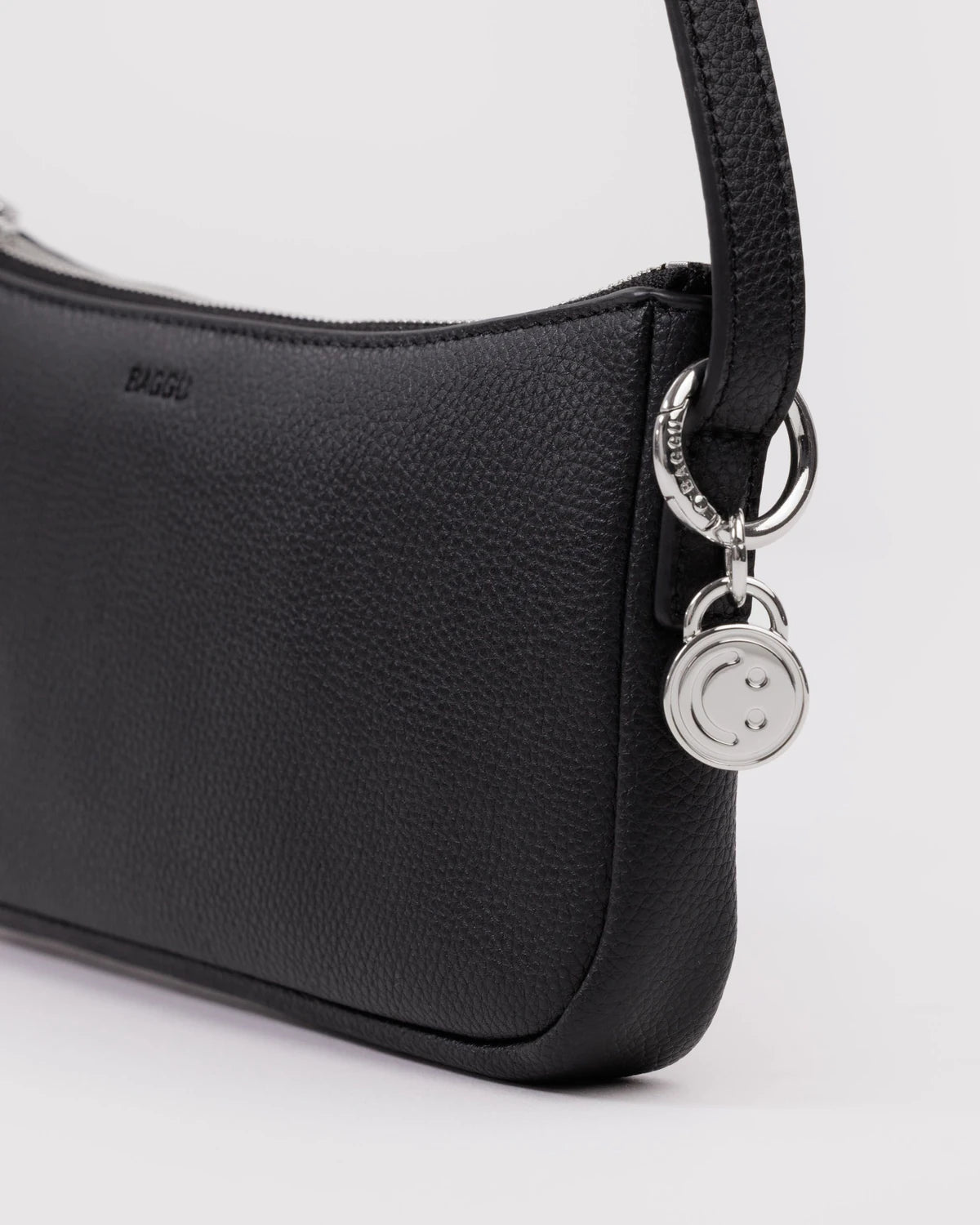 Black pebbled leather crossbody bag with silver smiley face charm and zip closure