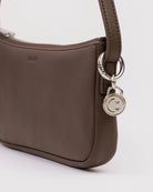 Brown leather shoulder bag with silver smiley face charm and zipper closure detail