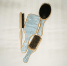 Set of four hair brushes with natural bristles and wooden handles in light blue and natural wood tones