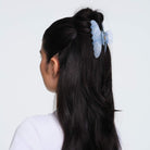 Blue marbled hair claw clip securing dark hair in half-up hairstyle, viewed from behind on model wearing white top