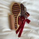 Burgundy velvet embellished slides with decorative bow and jeweled brooch, featuring striped insole and gold trim detailing