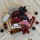 Assorted hair clips and barrettes in gingham, polka dot, and floral patterns with cherry details in red, pink, navy, and brown tones