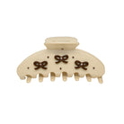 Cream-colored hair claw clip with brown bow decorations and rhinestone accents, featuring 7 teeth and a rounded top closure