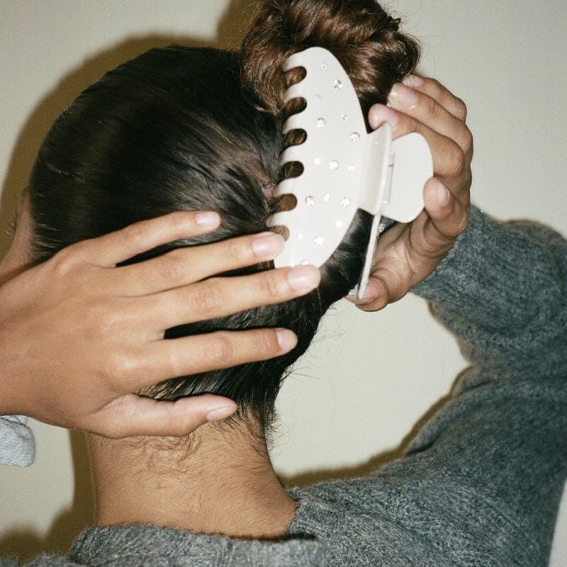 White wide-tooth comb with rounded teeth being used on dark hair, scalp massage and detangling tool