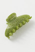 Green glittery gummy candy shaped like a leaf with wavy edges and textured surface dusted with sparkly sugar crystals