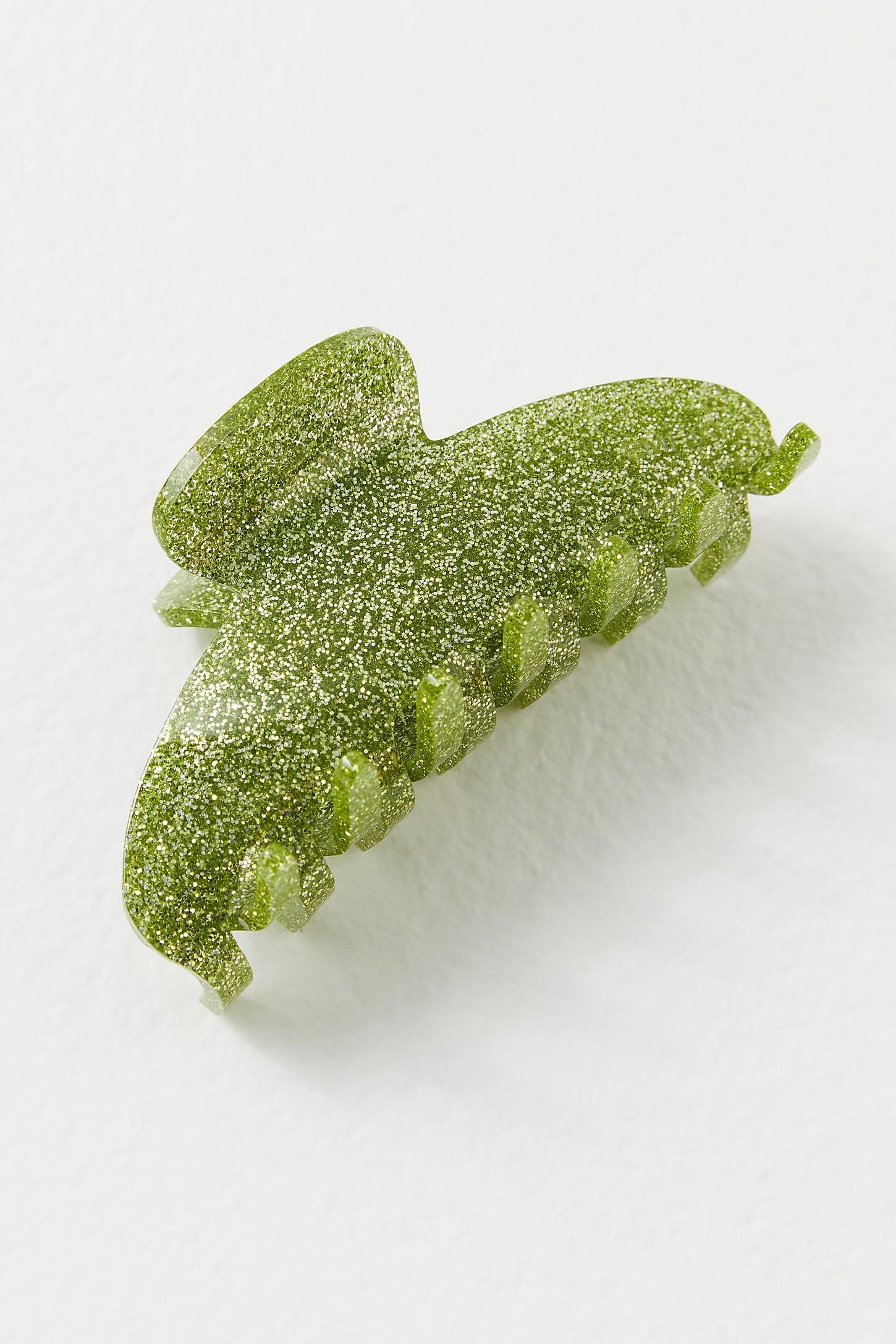 Green glittery gummy candy shaped like a leaf with wavy edges and textured surface dusted with sparkly sugar crystals