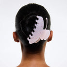 Purple butterfly-shaped hair claw clip with rhinestone embellishments and black teeth, shown securing dark hair in an updo