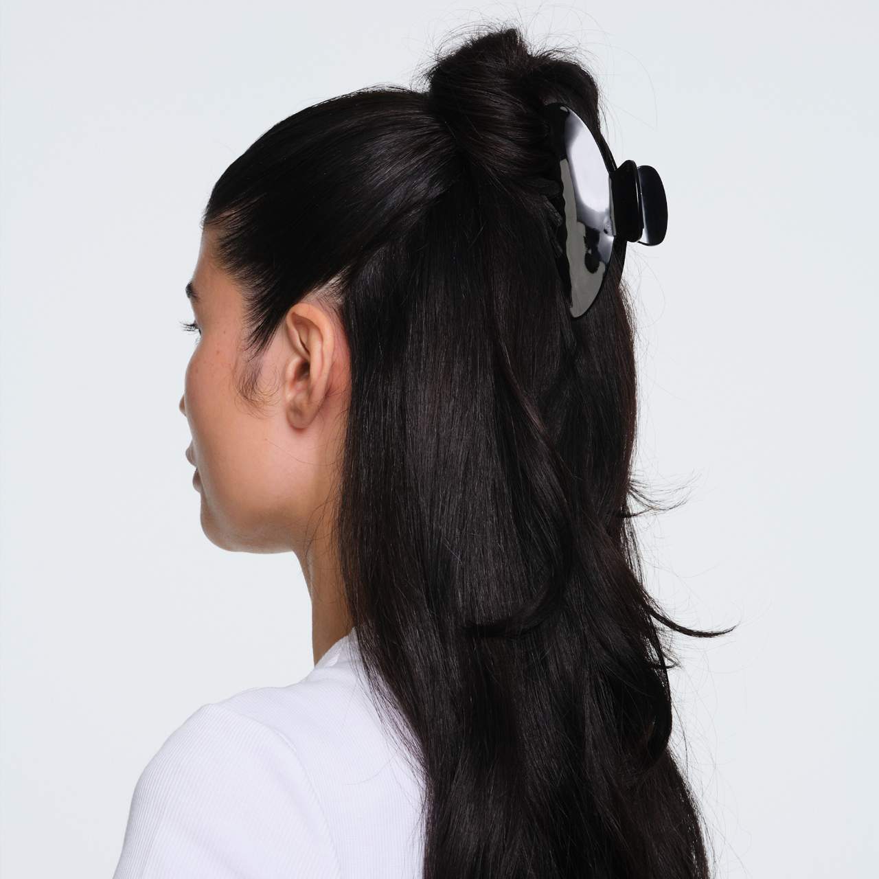 Black and silver hair claw clip securing a half-up hairstyle on long dark hair, side profile view