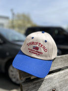 Tan and blue baseball cap with red THRIFTKND embroidery, American flag, and Sag Harbor NY address on front panel