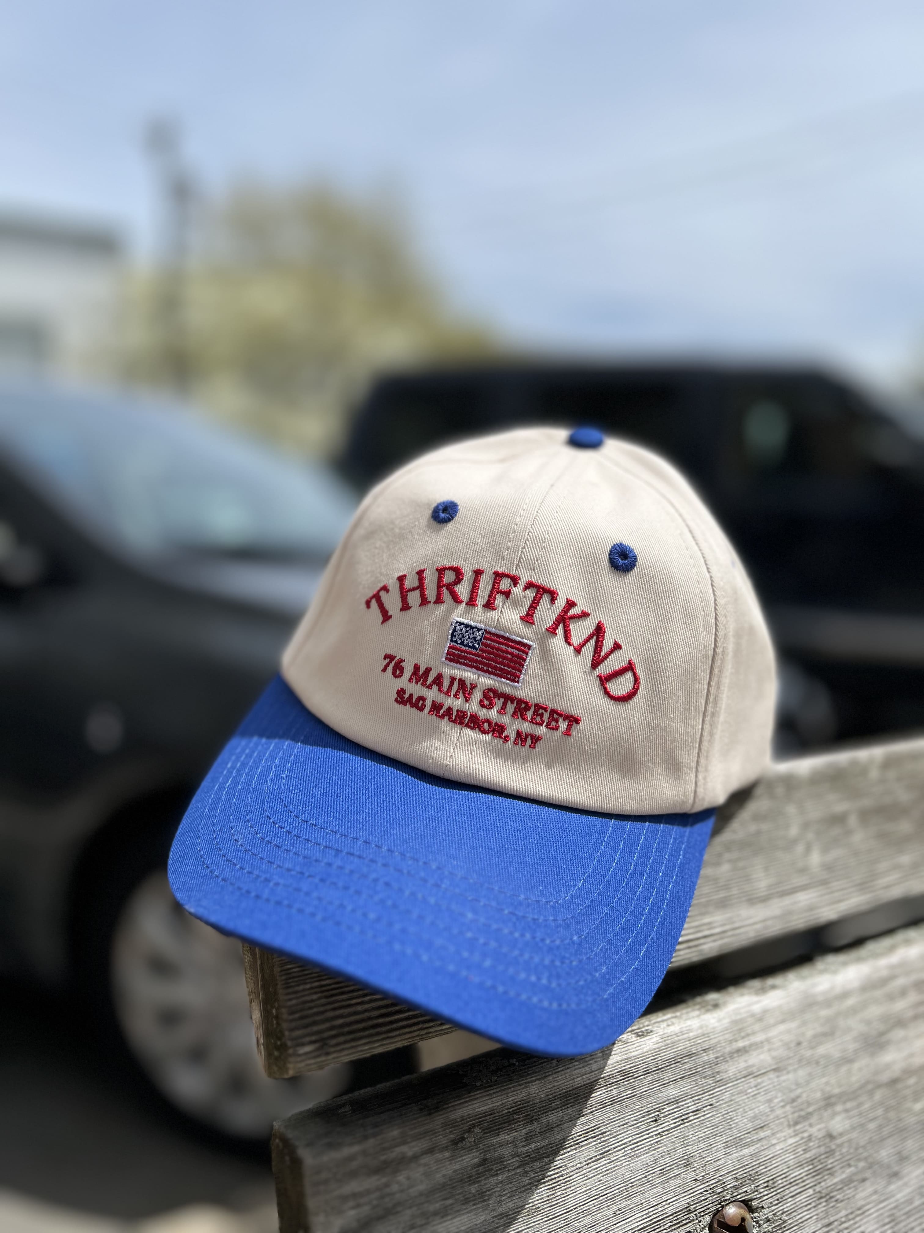 Tan and blue baseball cap with red THRIFTKND embroidery, American flag, and Sag Harbor NY address on front panel