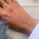 Delicate turquoise beaded bracelet on wrist with gold bangles, featuring small blue-green beads on thin chain