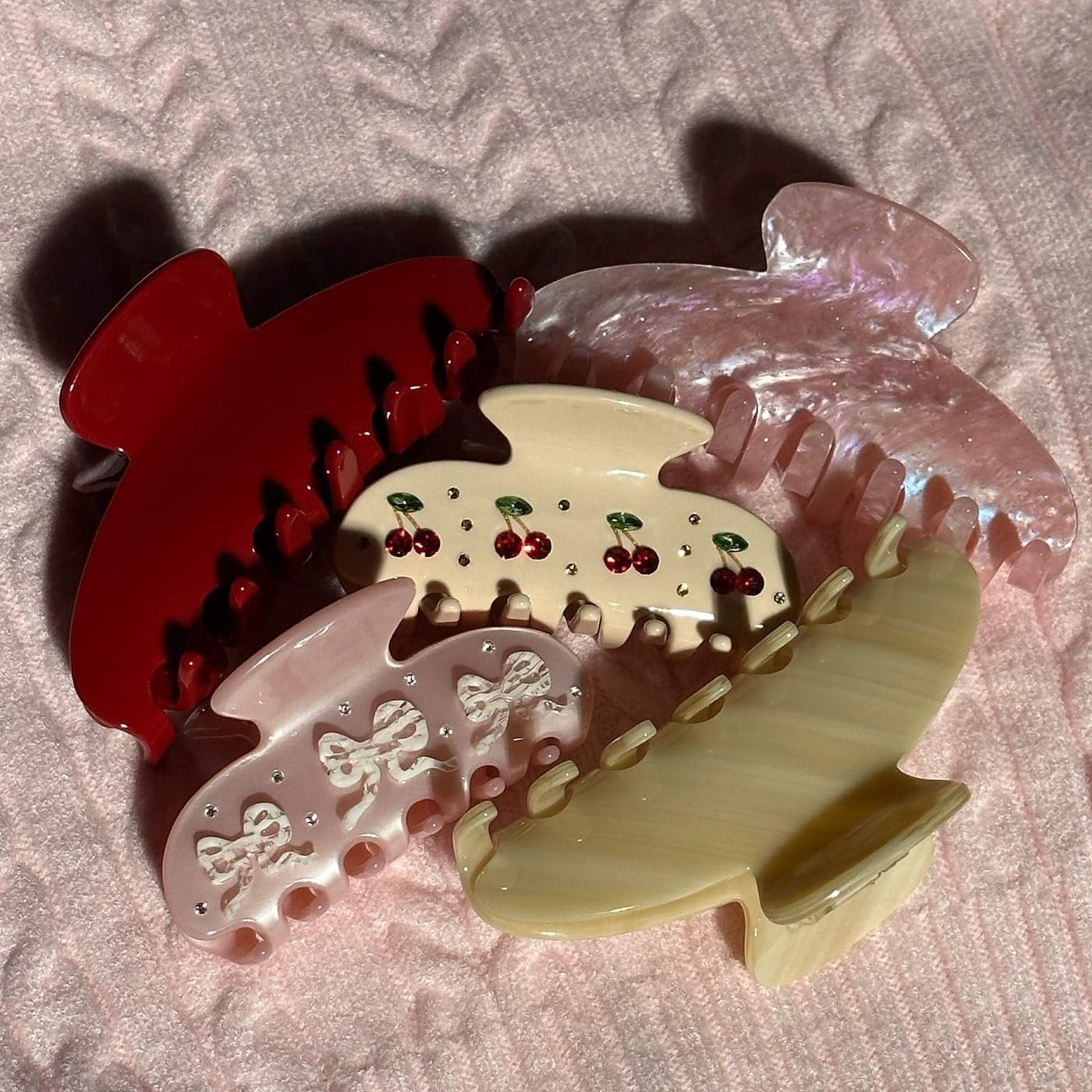 Set of four decorative hair claws in red, pink, and cream colors featuring cherry and bow designs with rhinestone details