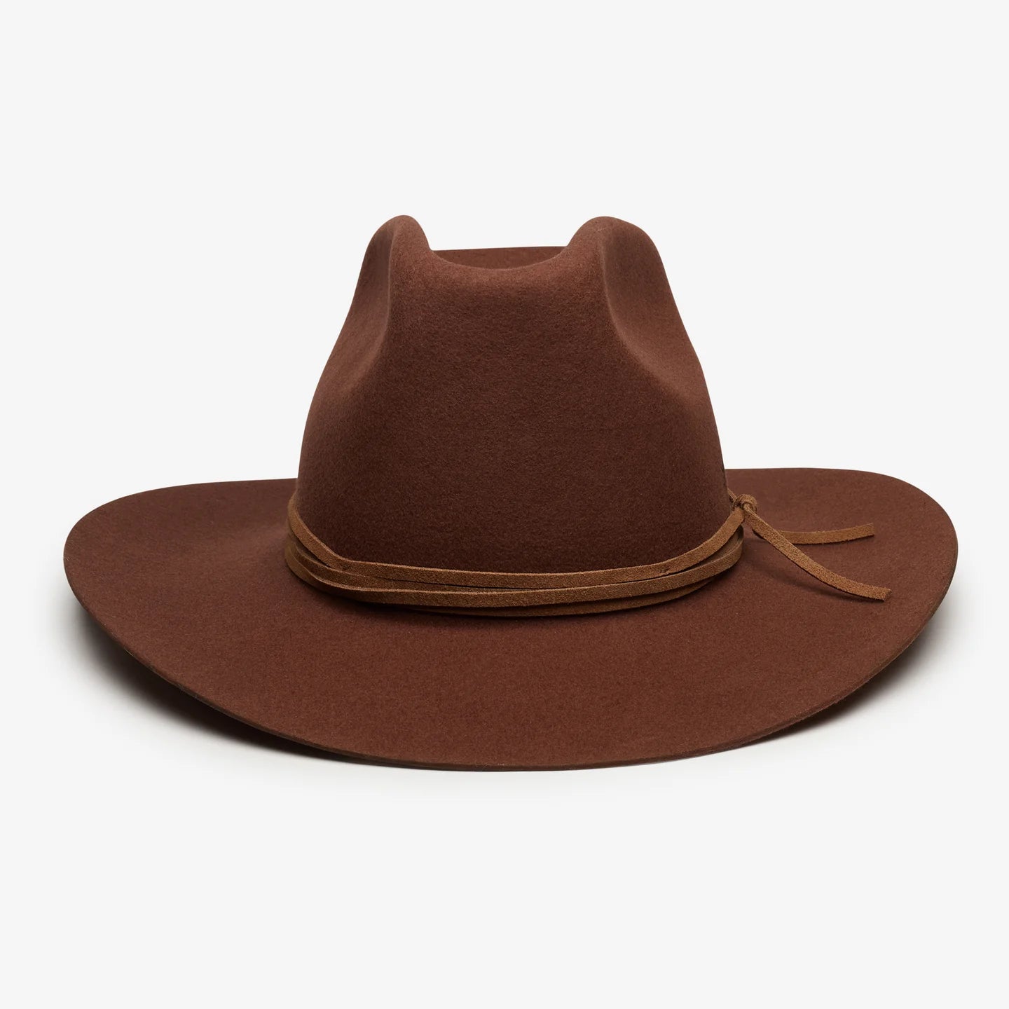 Brown felt wide-brim cowboy hat with leather band and bow detail resting on white surface