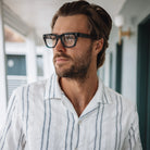 Man wearing glasses and a striped shirt in an indoor setting