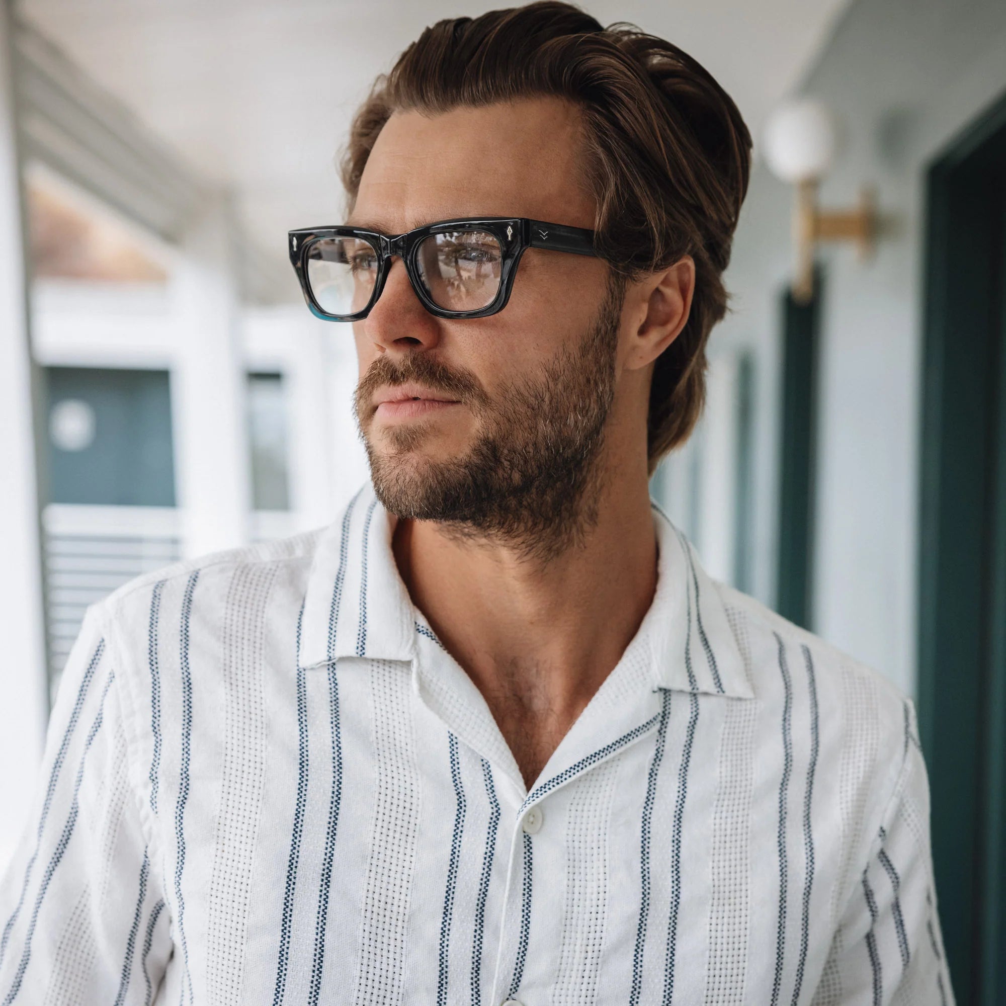 Man wearing glasses and a striped shirt in an indoor setting