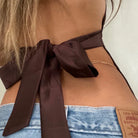 Close-up of a person wearing a brown halter top with a Levi's brand tag on jeans.