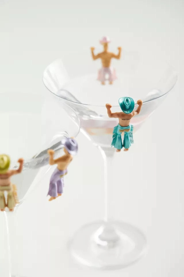 Small figurines of people around a martini glass on a white background
