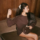Woman wearing brown ribbed cardigan with buttons and matching fuzzy handbag, styled with black skirt and hair clip