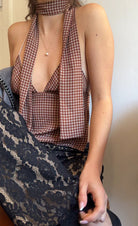 Woman wearing a checkered halter top with a blurred background