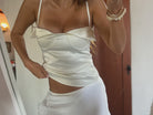 Person wearing a white dress with thin straps in a room.