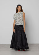 Black voluminous maxi skirt with gathered ruffle tier, taffeta fabric, floor-length, paired with polka dot top.