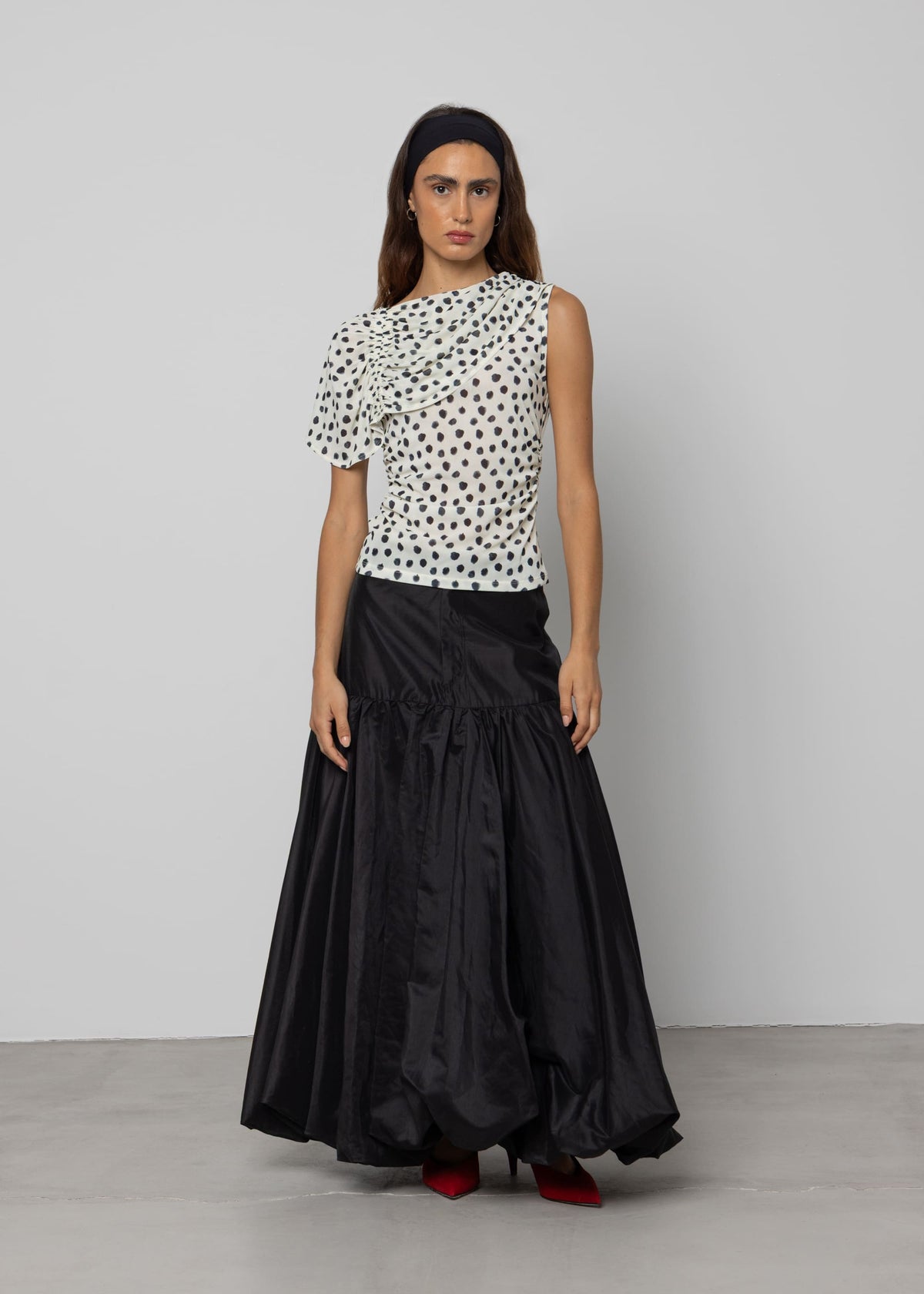 Black voluminous maxi skirt with gathered ruffle tier, taffeta fabric, floor-length, paired with polka dot top.