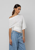 White asymmetric off-shoulder draped top with ruched waist detail and elbow-length sleeves