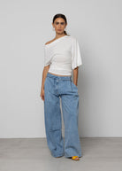 Wide-leg light wash blue denim jeans with pleated front, folded waistband detail, and relaxed silhouette.