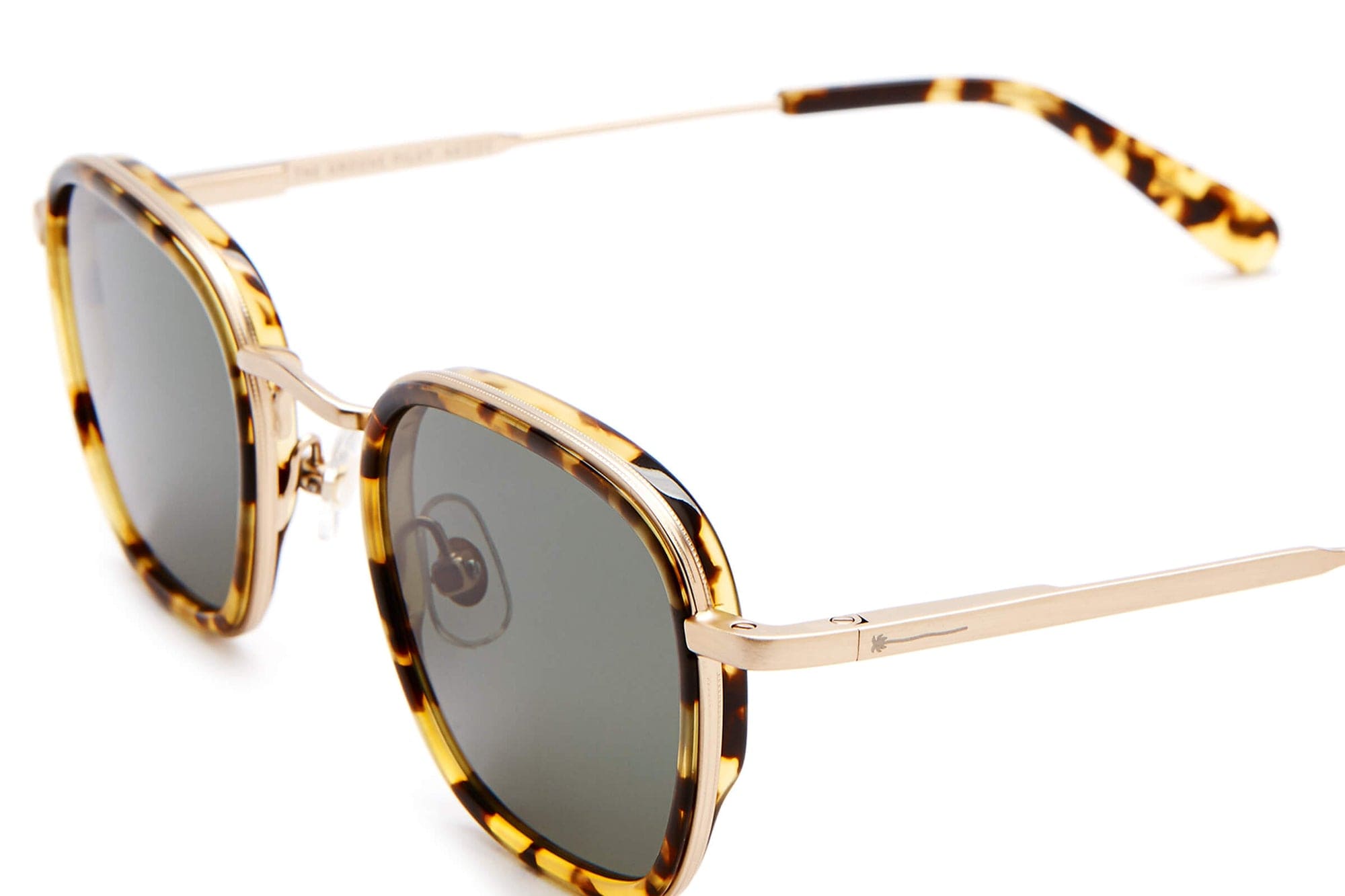 Tortoiseshell square sunglasses with gold metal temples and dark tinted lenses on white background