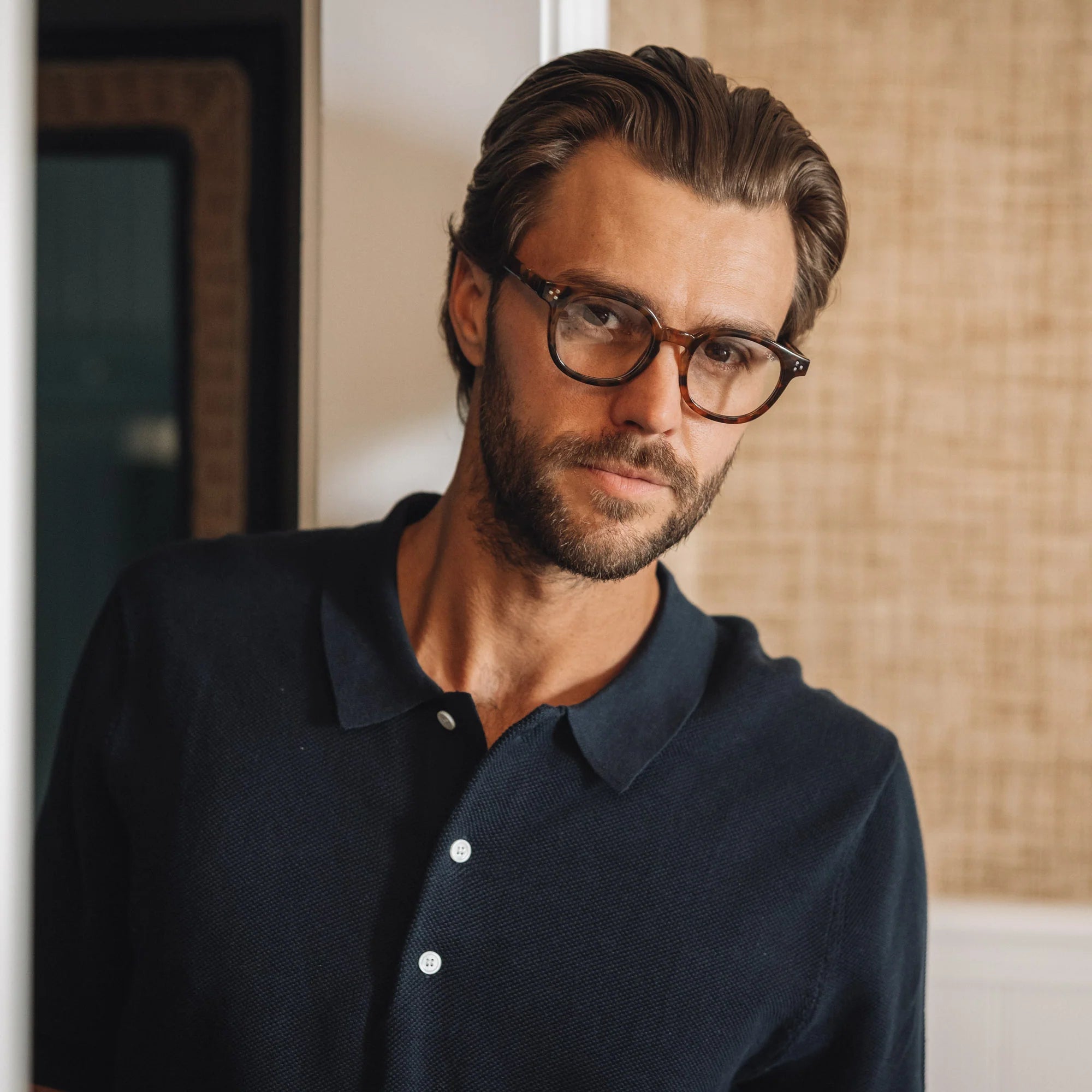 Man wearing glasses and a dark shirt indoors