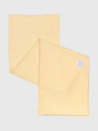 Yellow textured cleaning cloth with pink label tag, shown folded on gray background