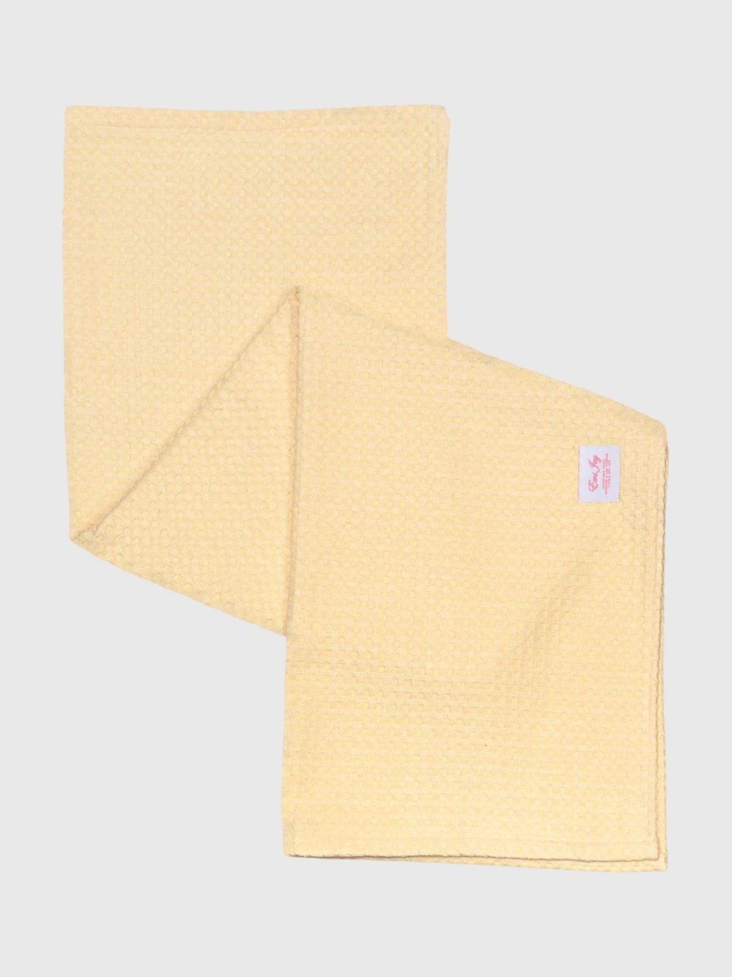 Yellow textured cleaning cloth with pink label tag, shown folded on gray background