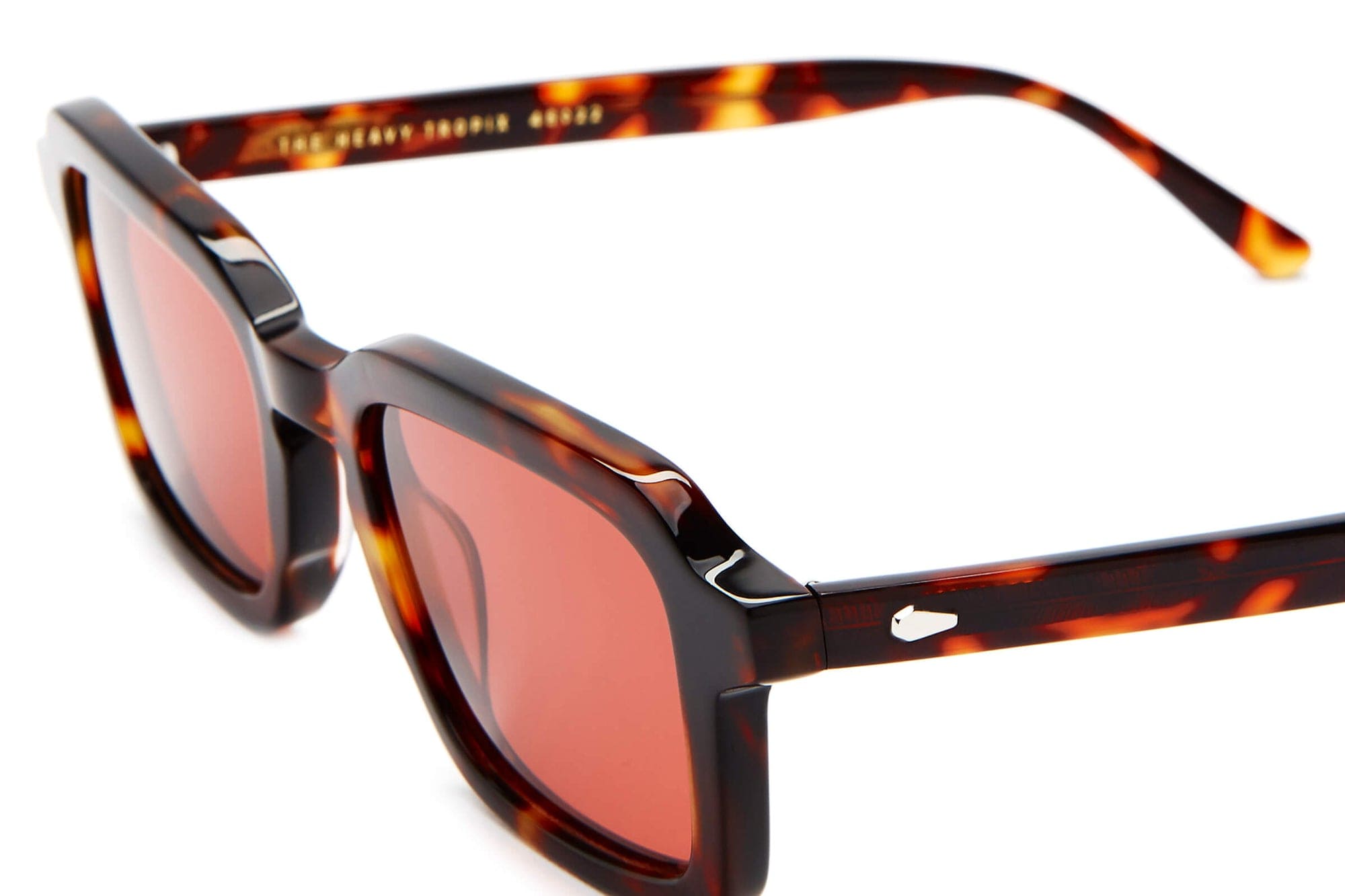 Sunglasses with tortoiseshell frame and red lenses on a white background