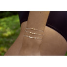Delicate gold wire wrap bracelet with small pearl beads worn on upper arm