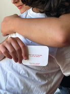 Person holding white card with red text reading "What are you feeling a lot of lately?" from We're Not Really Strangers dating card game