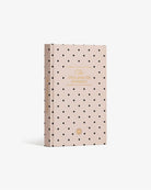 Pink polka dot hardcover journal with gold foil text reading "The Five Minute Journal" and decorative sun emblem
