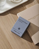 Beige and blue productivity planners on wooden desk with white tray, featuring linen-textured covers and minimalist design