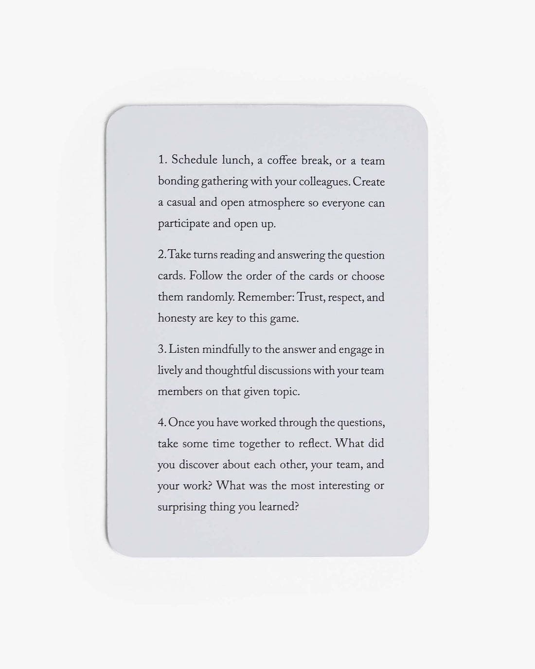 Gray rounded rectangle card with black text containing 4 numbered instructions for a team bonding card game activity