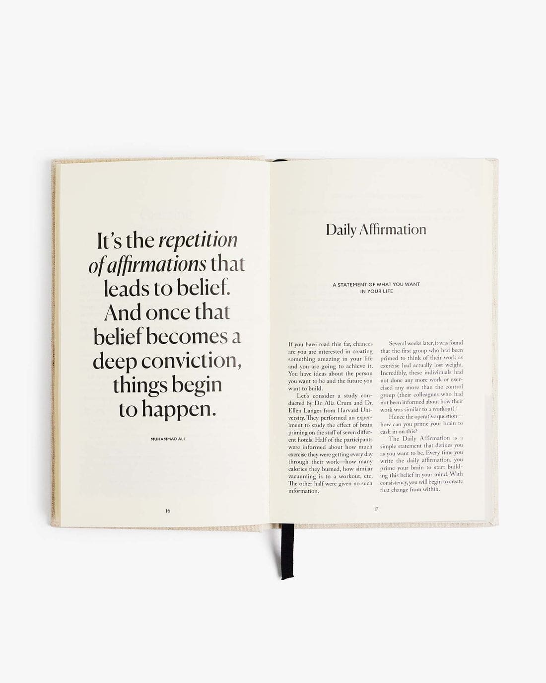 Open journal showing daily affirmation pages with black text on cream paper, featuring Muhammad Ali quote about repetition and belief