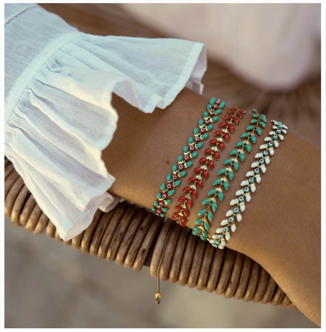 Colorful beaded bracelets in turquoise, red, and white stacked on wrist with wooden bead bracelet and white textured sleeve